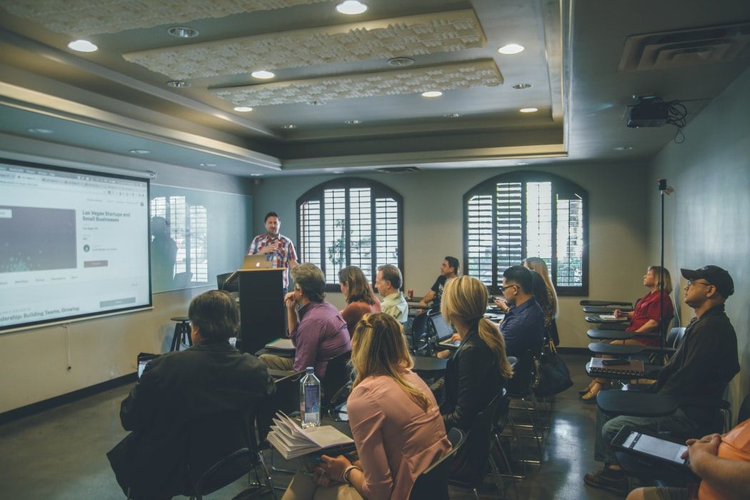A group of people are sitting in a classroom watching a presentation.