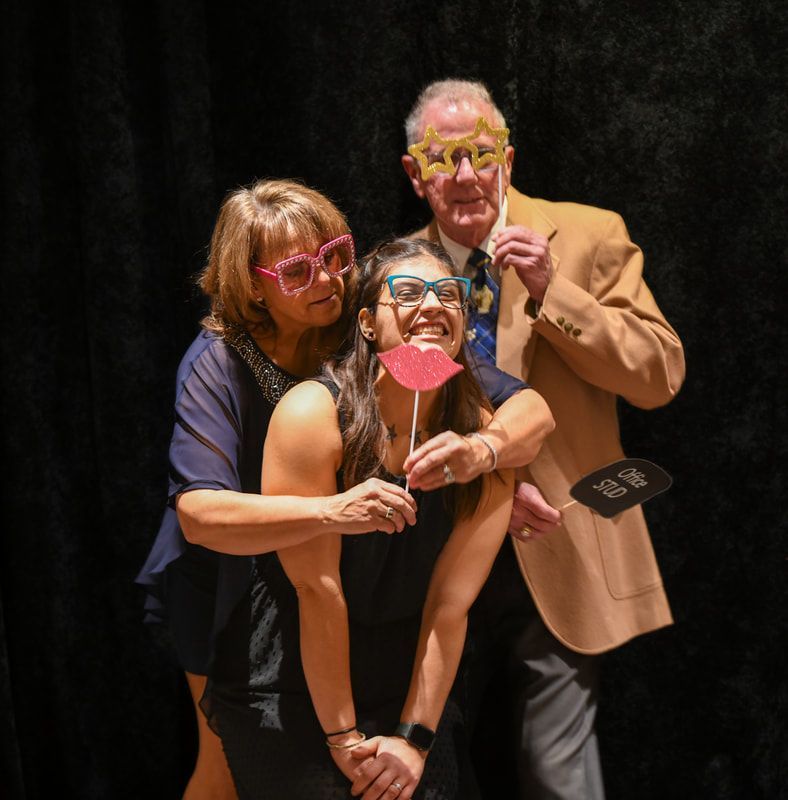 A man and two women pose for a picture with a prop that says ' i love you ' on it