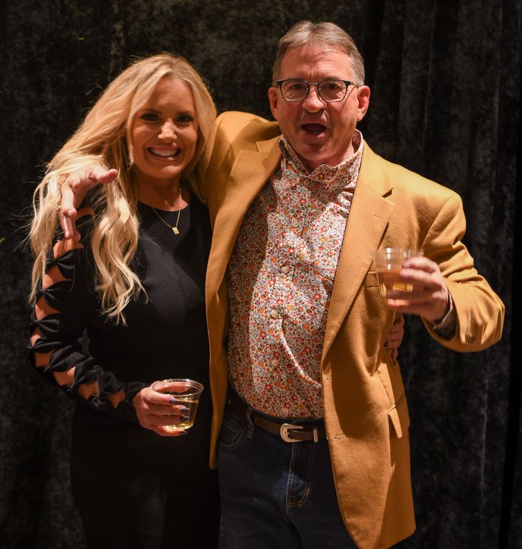 A man and a woman are posing for a picture while holding drinks