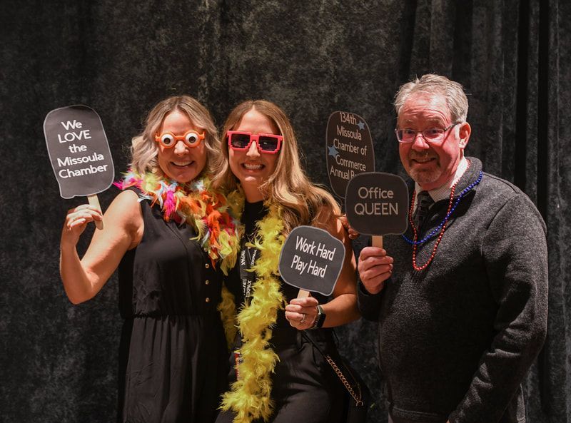 Three people are posing for a picture in a photo booth while holding signs.