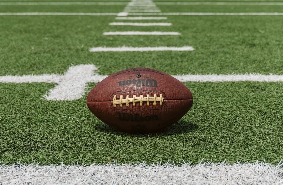 A football is sitting on the edge of a football field.