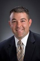 A man in a suit and tie is smiling for the camera.