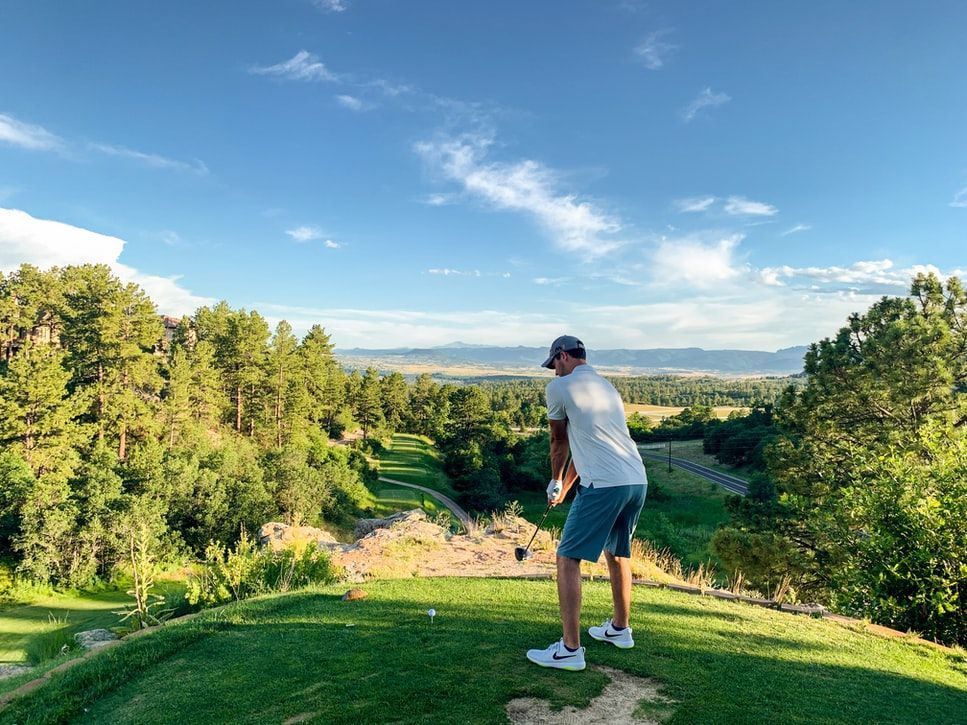 A man is swinging a golf club on a golf course.