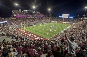 A crowd of people are watching a football game in a stadium.