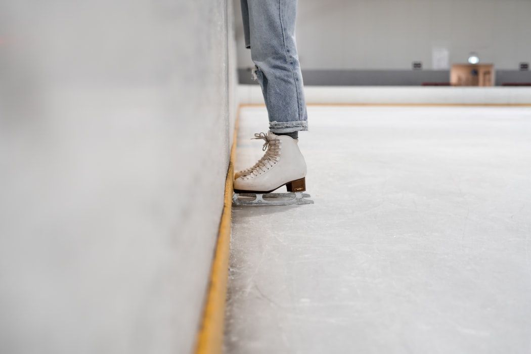 A person is standing on a ice rink wearing ice skates.
