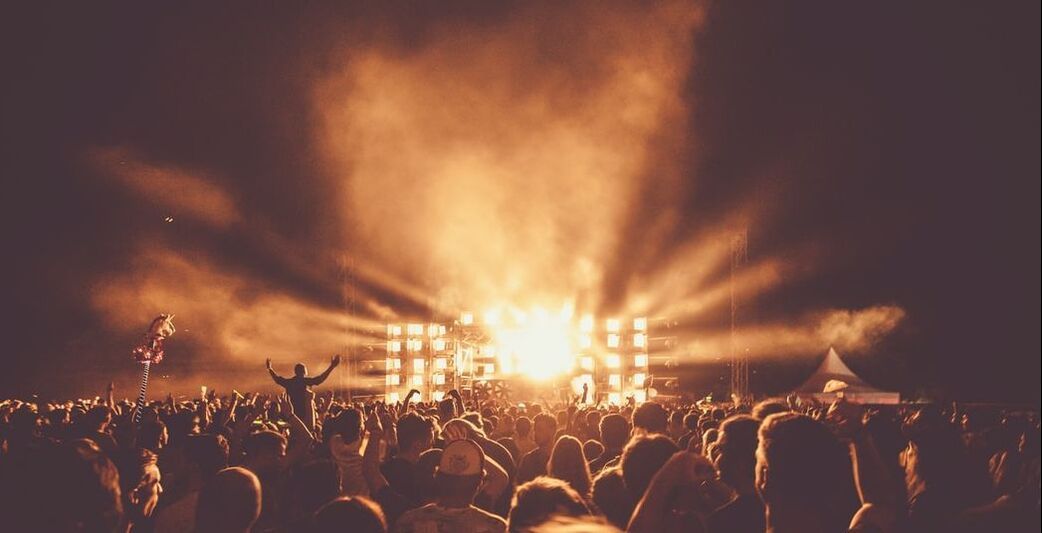 A crowd of people standing in front of a stage at a concert.