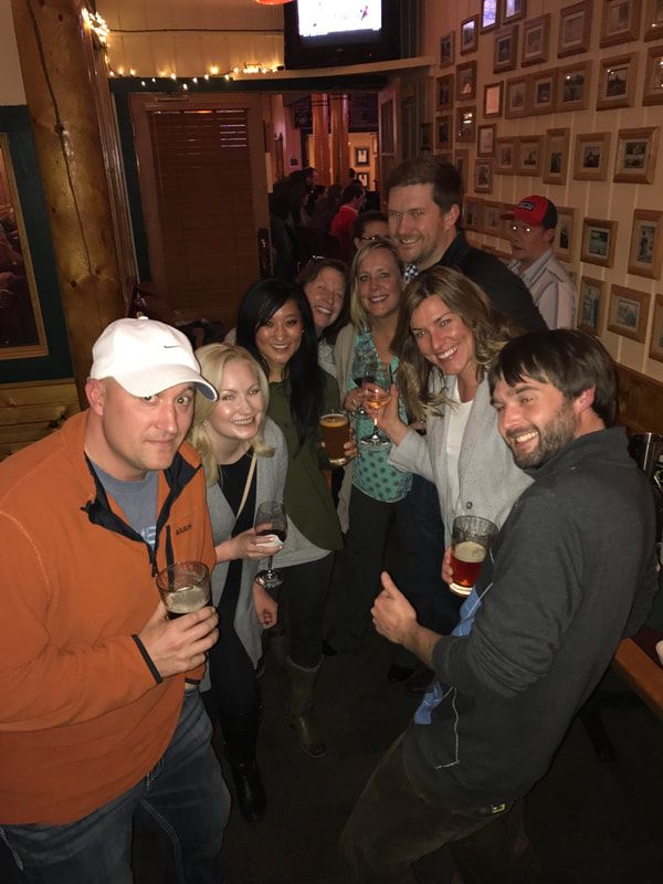 A group of people are standing in a room holding beer glasses.