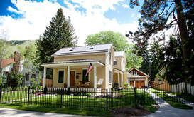 A house with a porch and a fence in front of it.