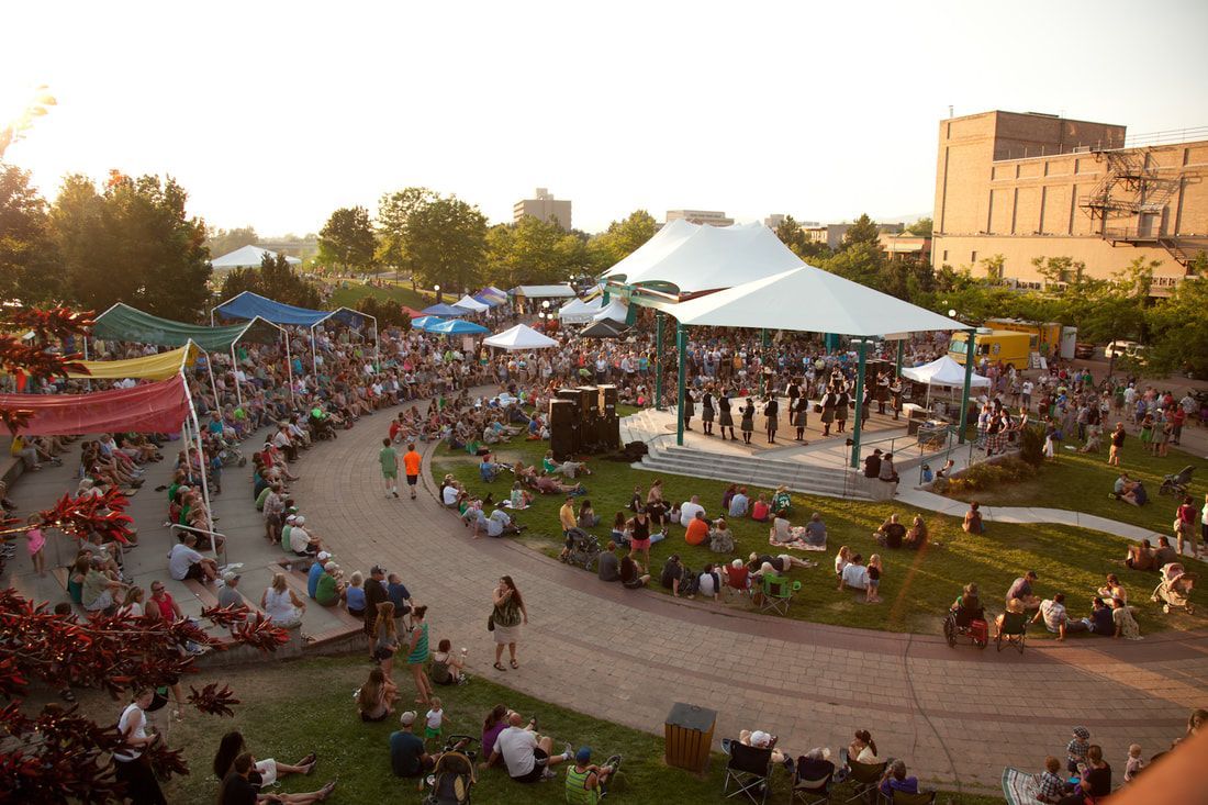 A large crowd of people are gathered in a park for a concert.
