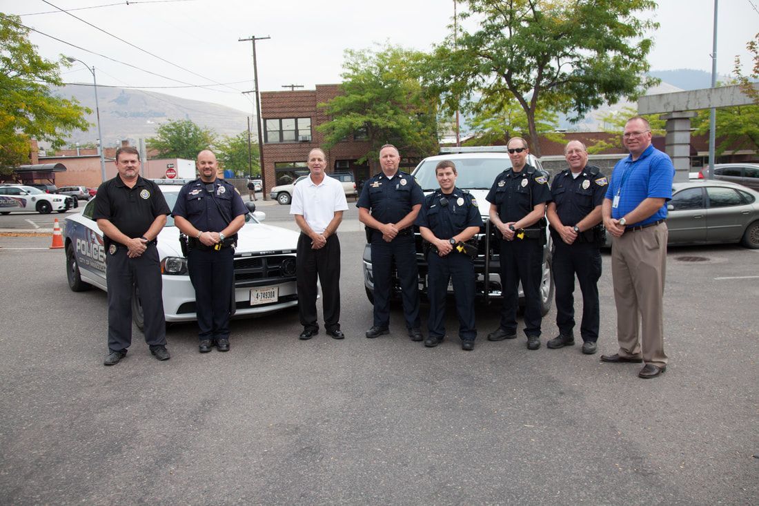A group of police officers are posing for a picture in front of a police car
