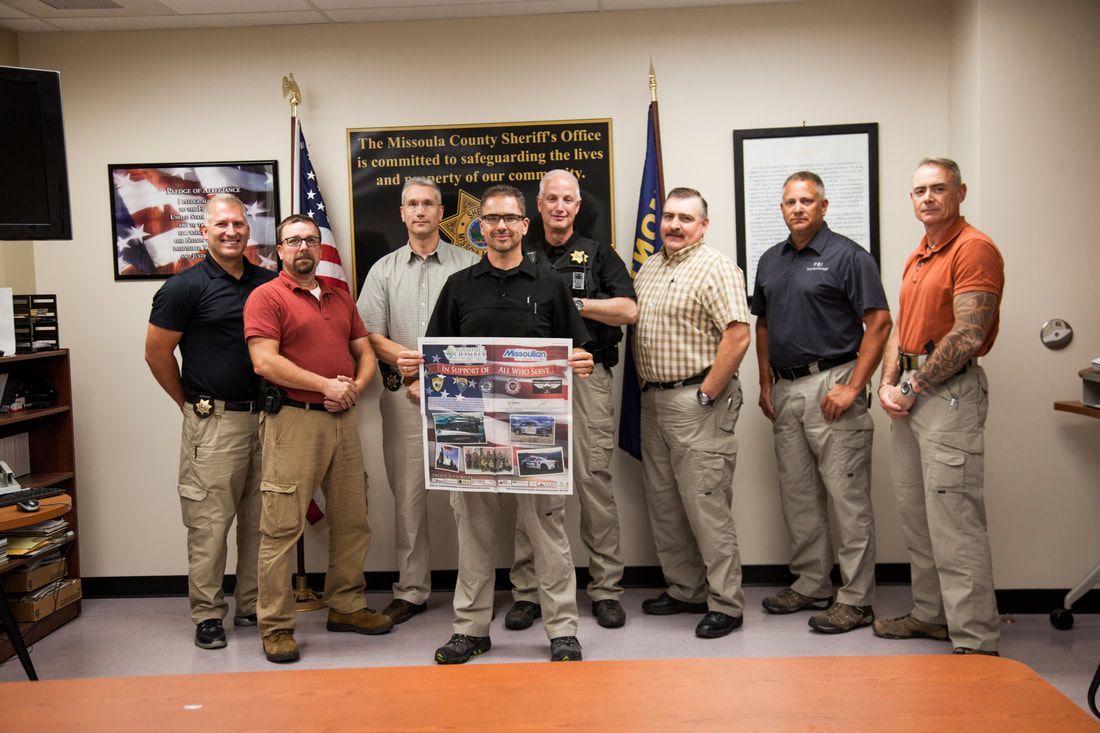 A group of men are standing in a room holding a poster.