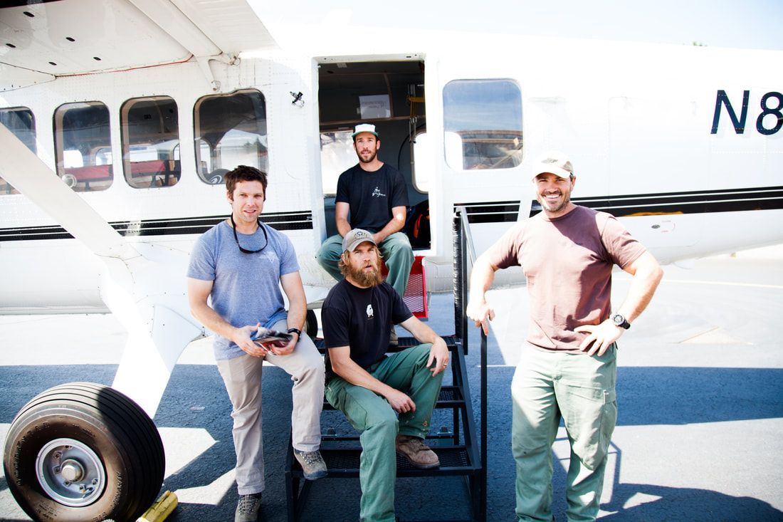 Four men are standing in front of an airplane with the number n8 on it