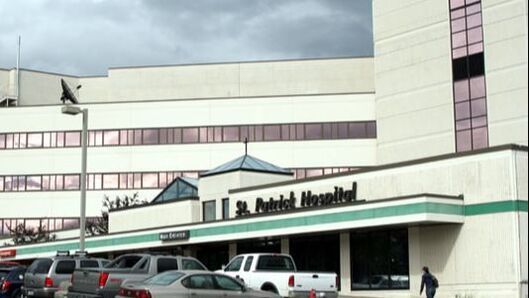A hospital with a lot of cars parked in front of it