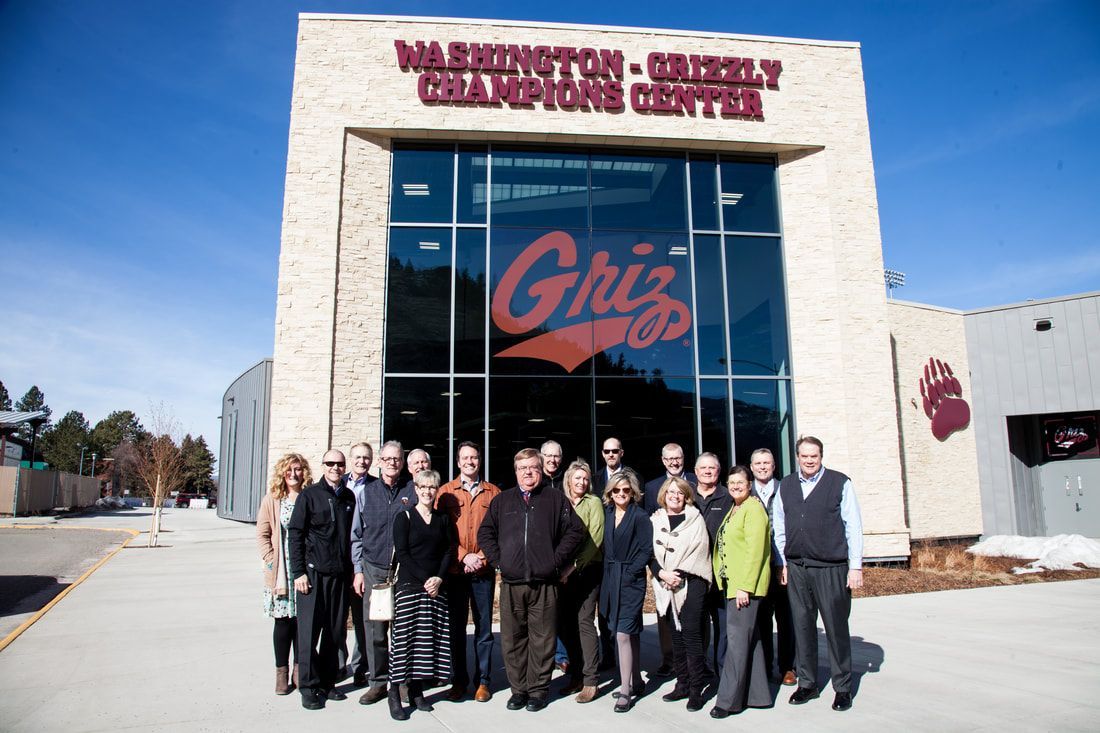 A group of people standing in front of a building that says griz
