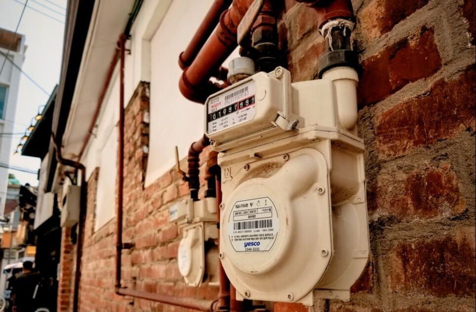 A gas meter is attached to a brick wall.