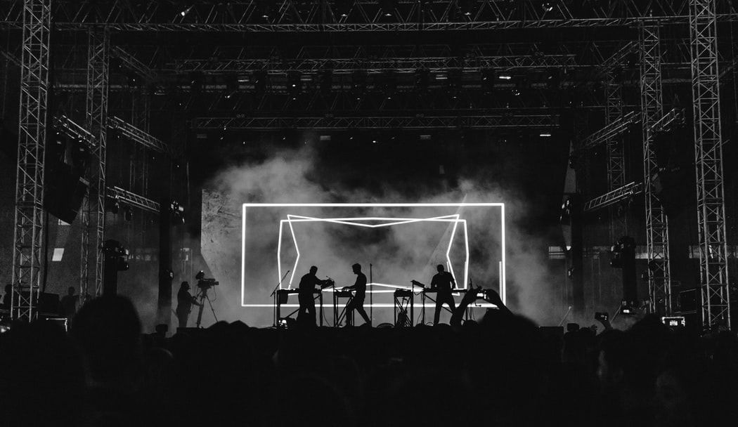 A black and white photo of a group of people playing instruments on a stage.