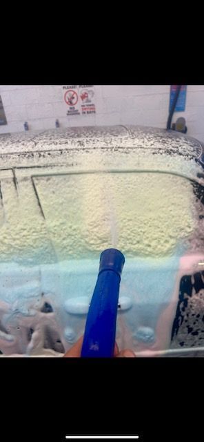 A person is cleaning the windshield of a car with a spray bottle.