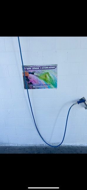 A hose is attached to a wall with a sign on it.