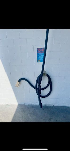 A white wall with a sign on it and a hose attached to it.