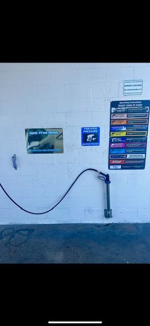 A black hose is hanging from a white wall.