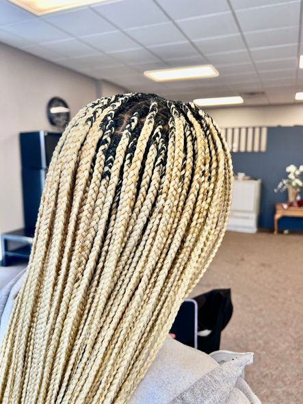 Person with blonde box braids in a salon.