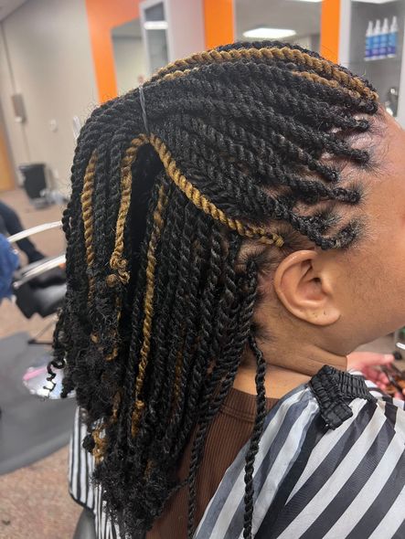 Woman with black and gold twisted braids in a salon.