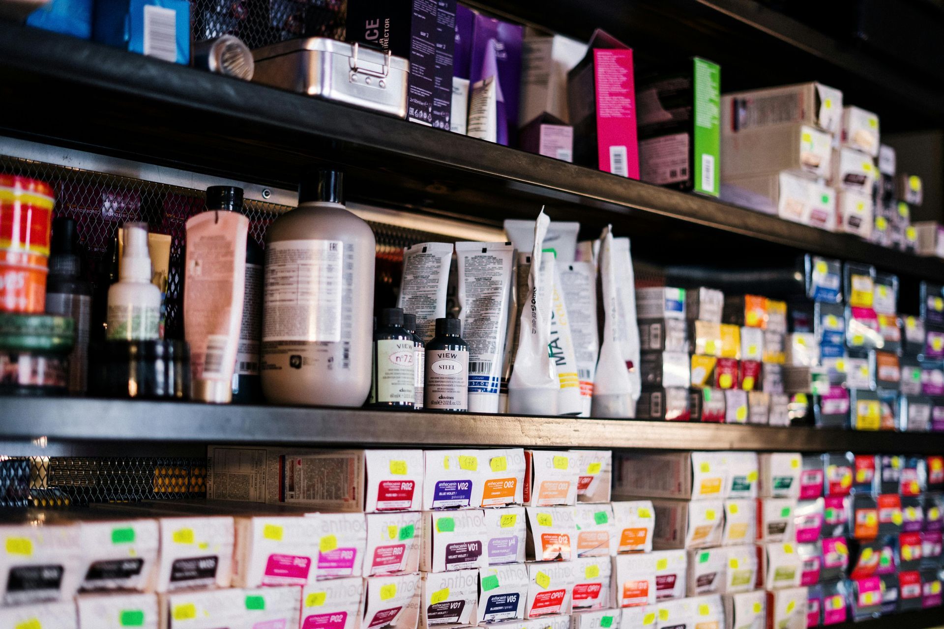 Shelves stocked with hair dye and styling products in a salon setting. Various colors are displayed.