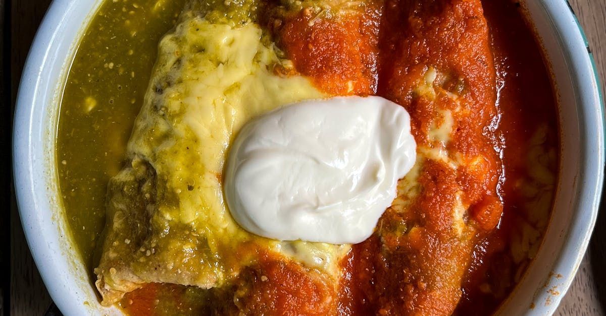A close up of a bowl of food with sour cream on top.