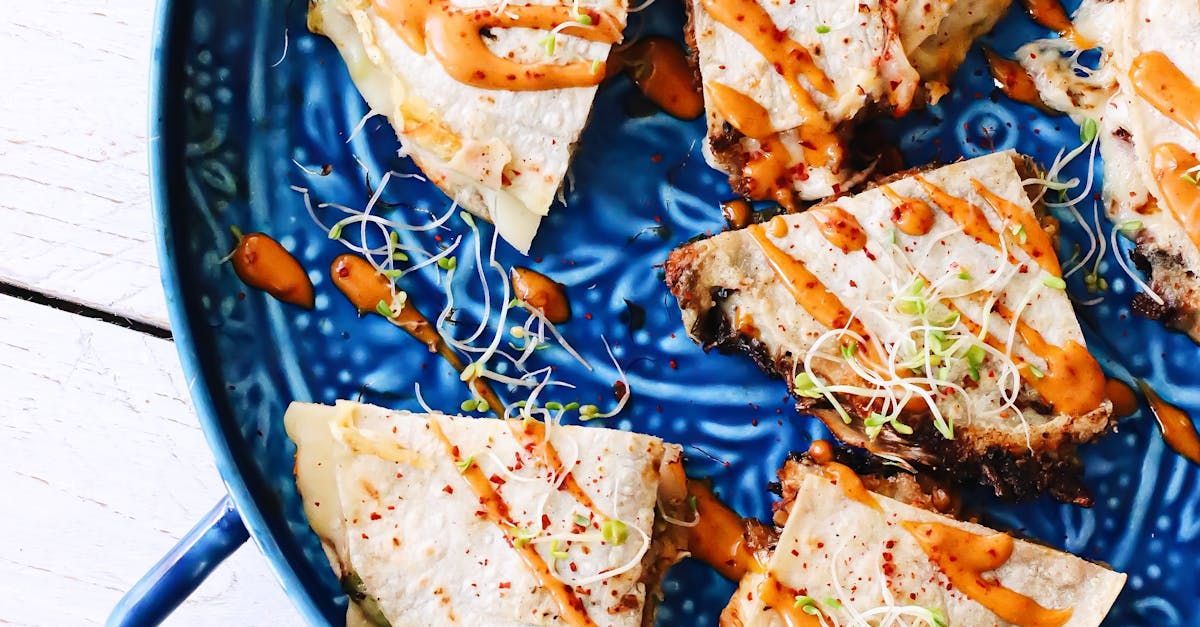 A close up of a blue plate topped with quesadillas on a table.