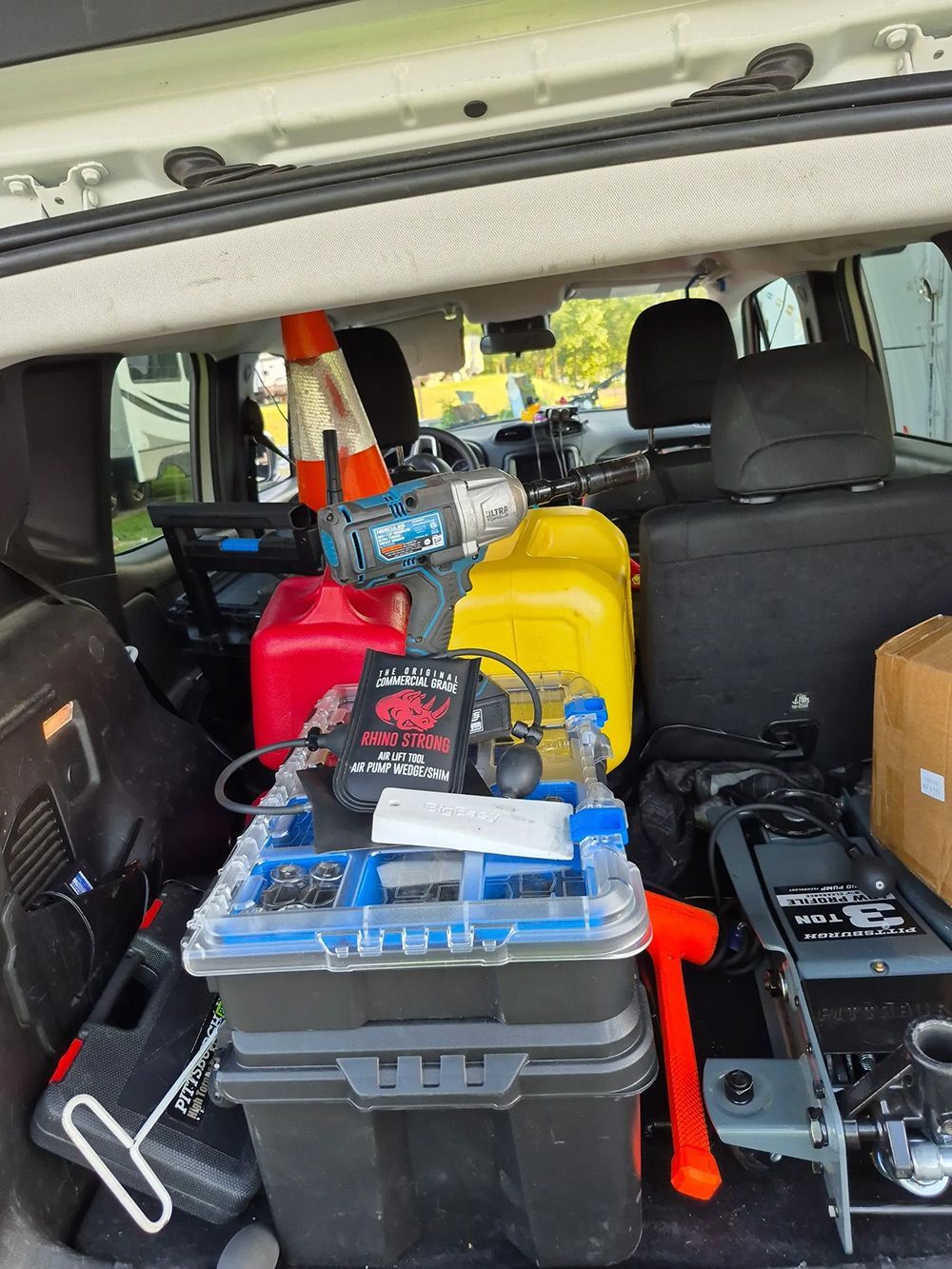 A car trunk filled with tools, fuel cans, and a toolbox, likely for repairs or construction.