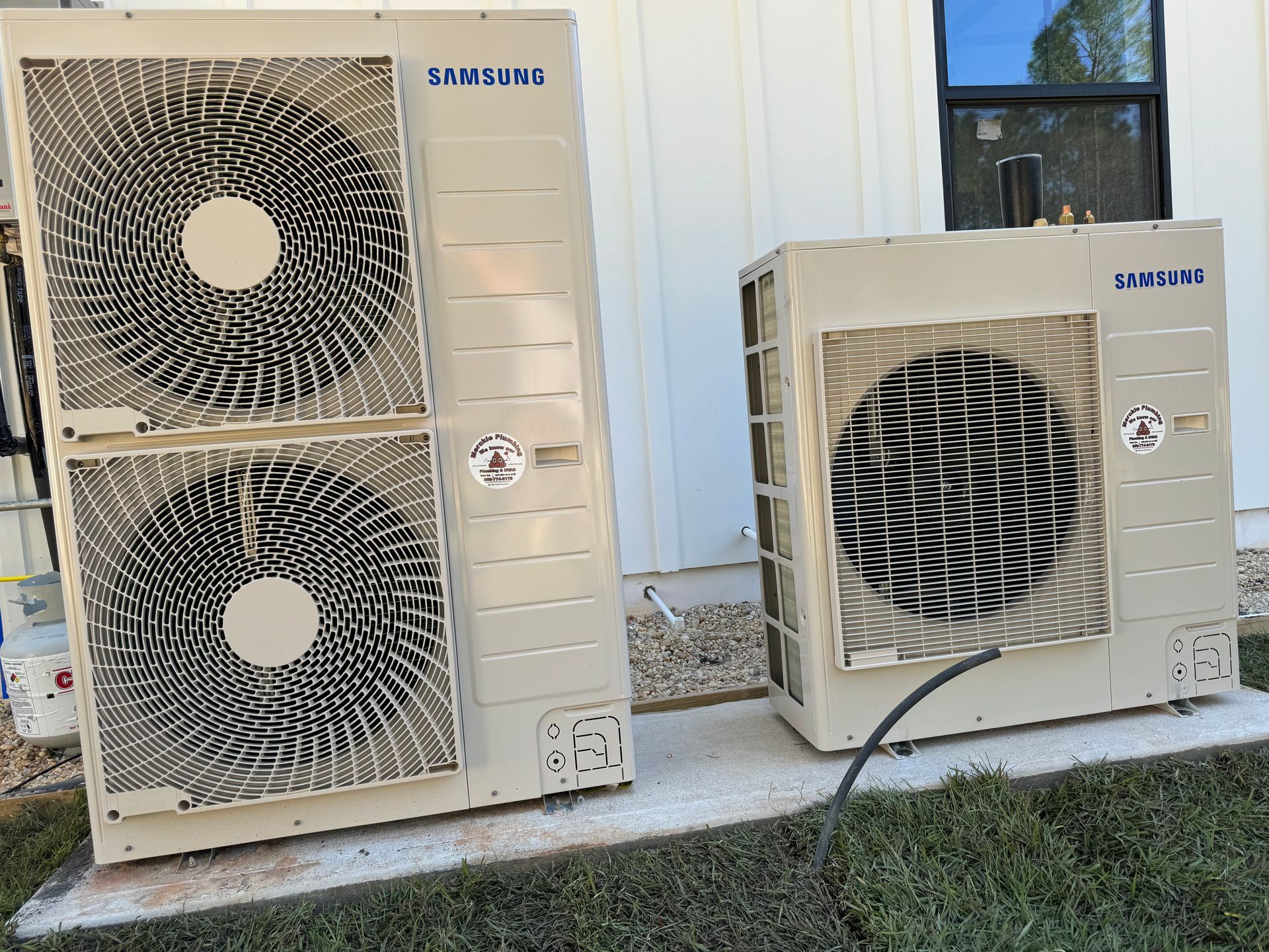 Two beige Samsung air conditioning units outside, on concrete.