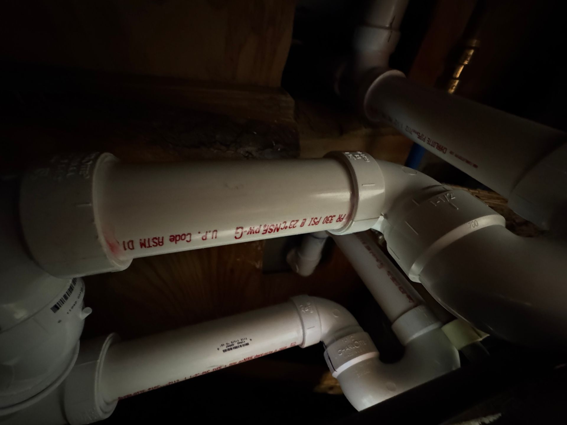 White PVC pipes and fittings in a dim, enclosed space.