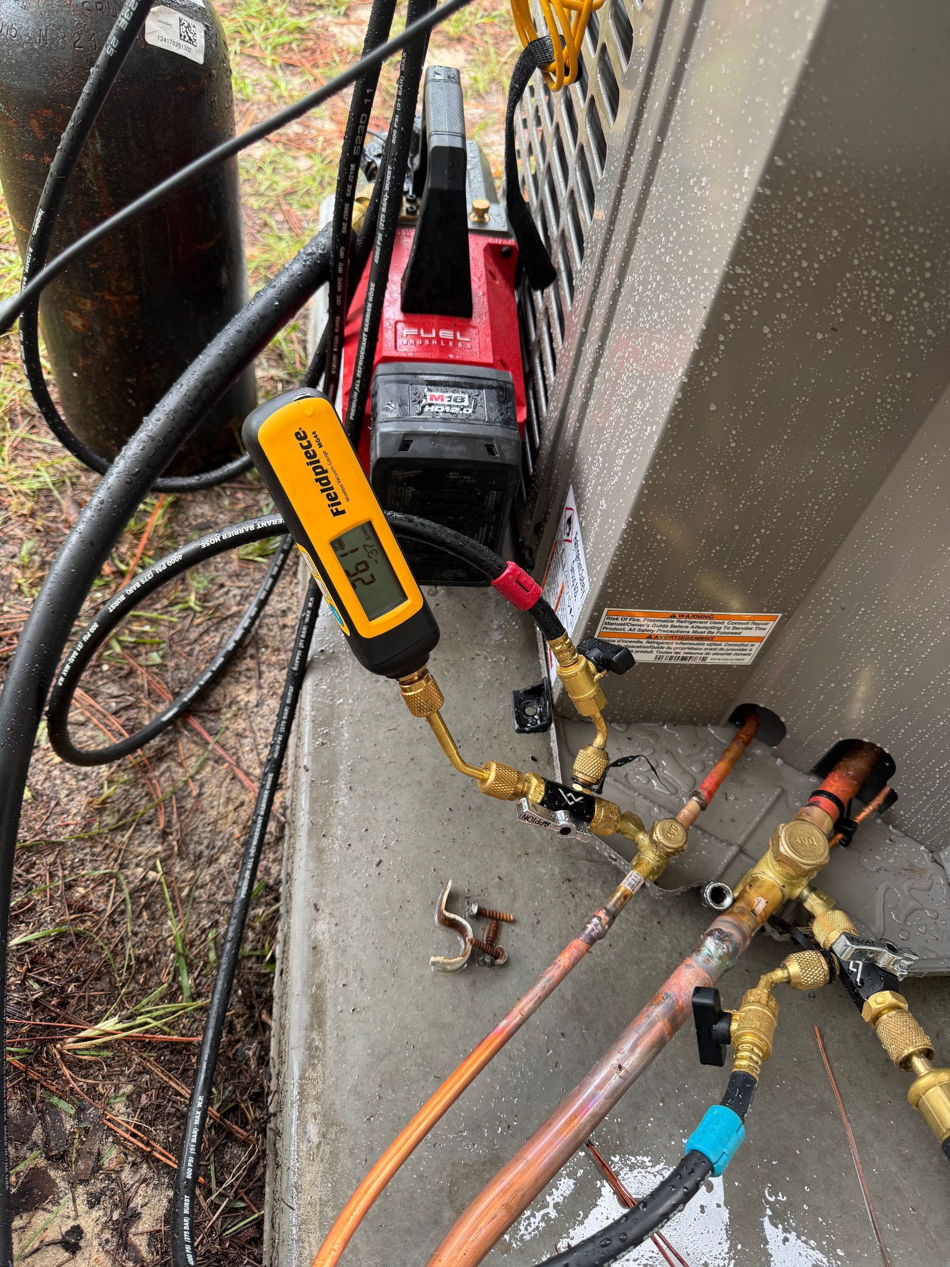 A welding setup with gauges, hoses, and a red welding machine on a concrete structure outdoors.