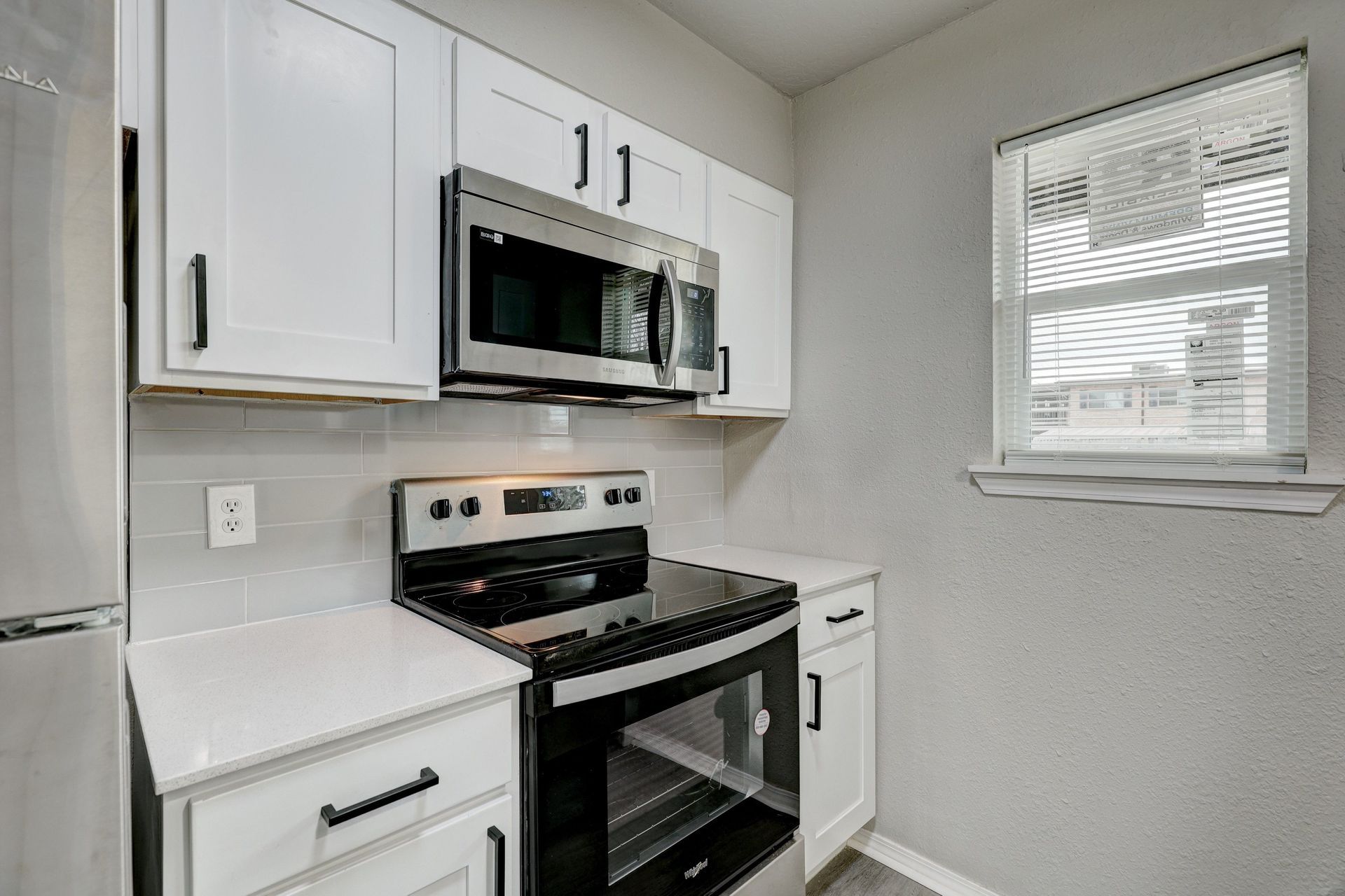 White kitchen with stainless steel appliances and a window.