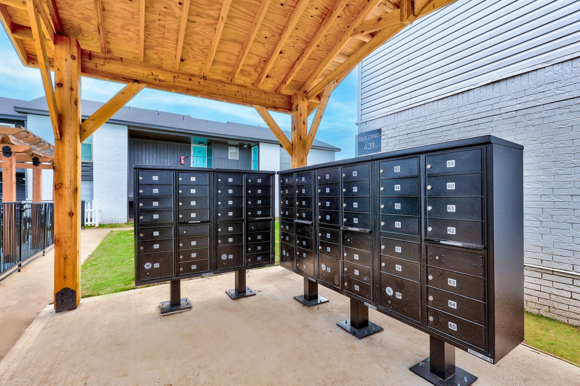 Black mailboxes under a wooden awning at an apartment complex.
