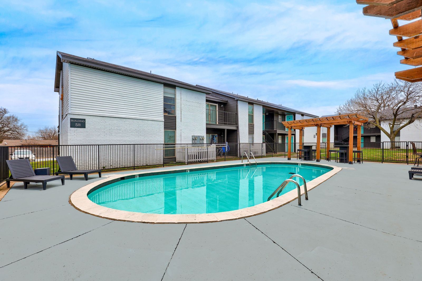 Apartment building with a pool and deck on a sunny day.