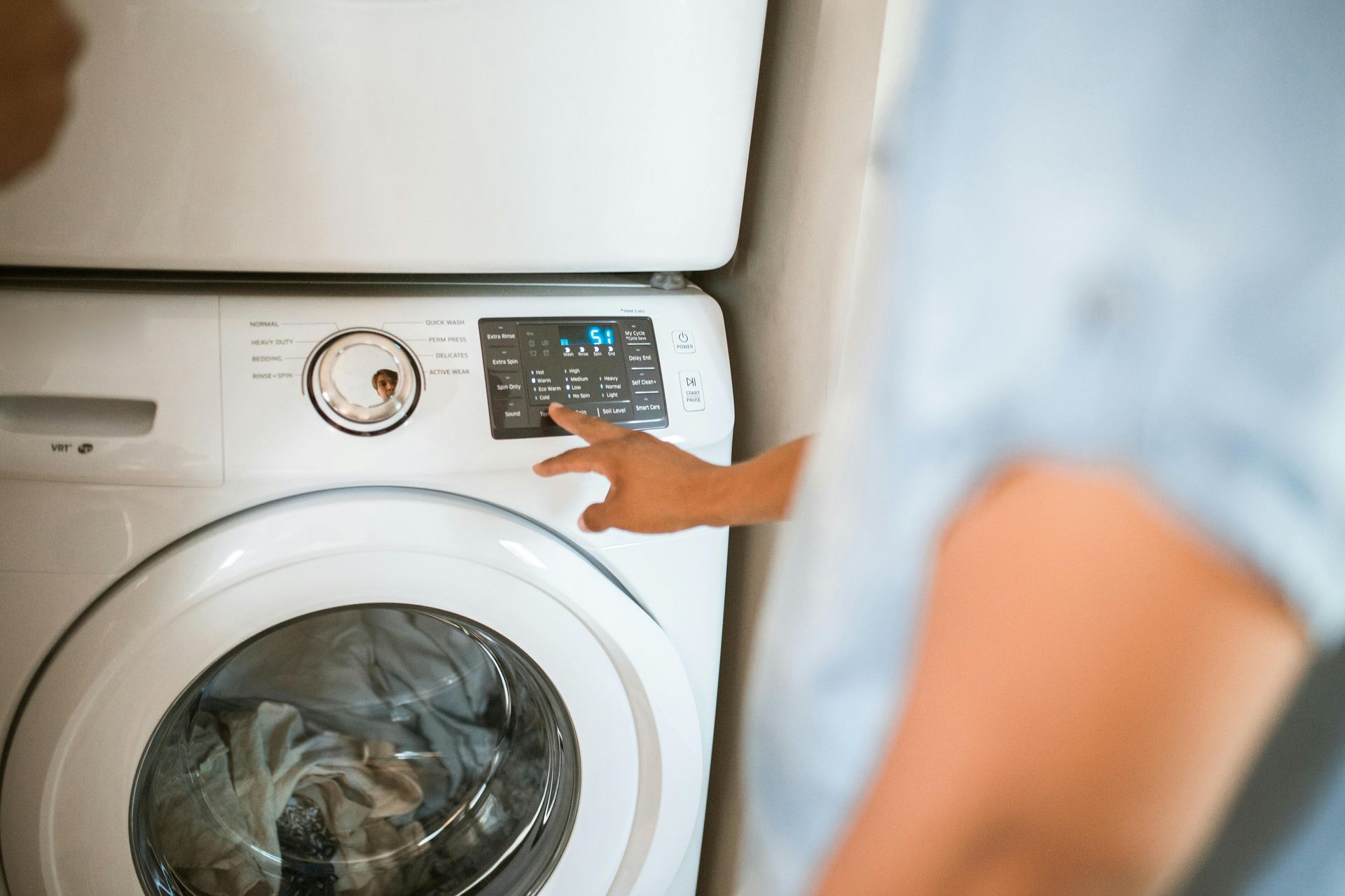 A person is pressing a button on a washing machine.