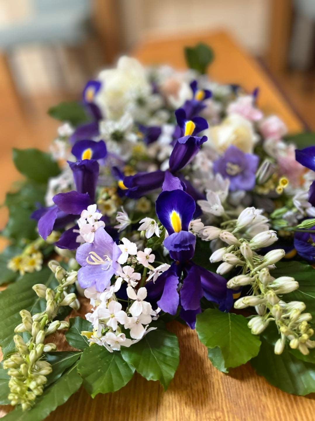 A bunch of purple and white flowers are sitting on a wooden table.