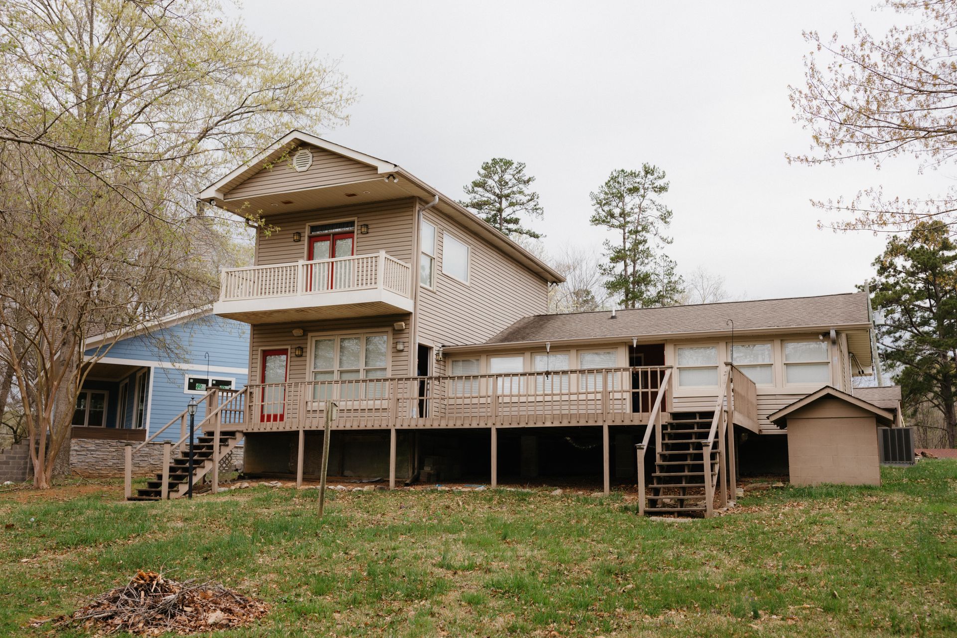 A large house with a large deck is sitting on top of a lush green field.