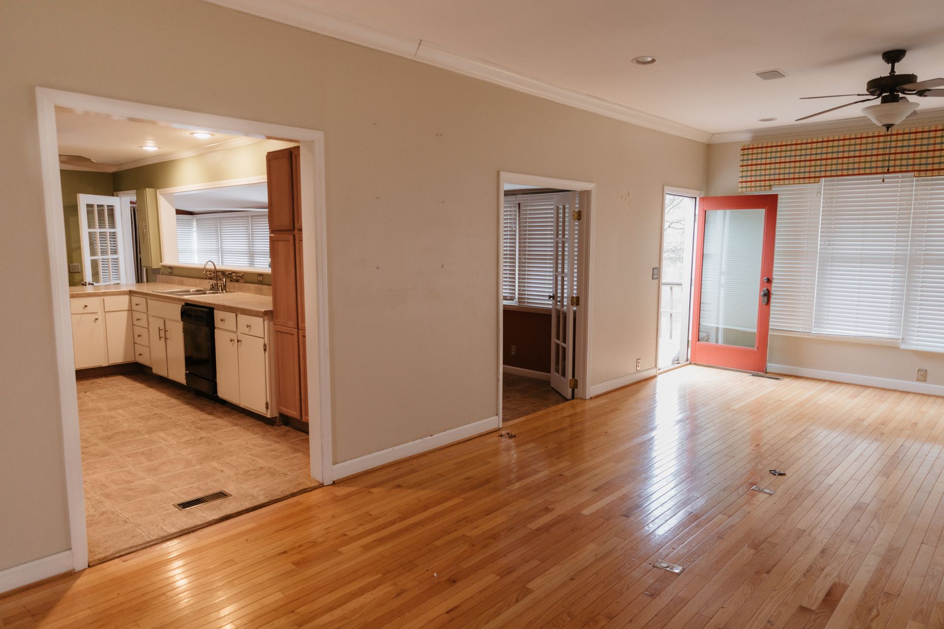 An empty house with hardwood floors and a kitchen.