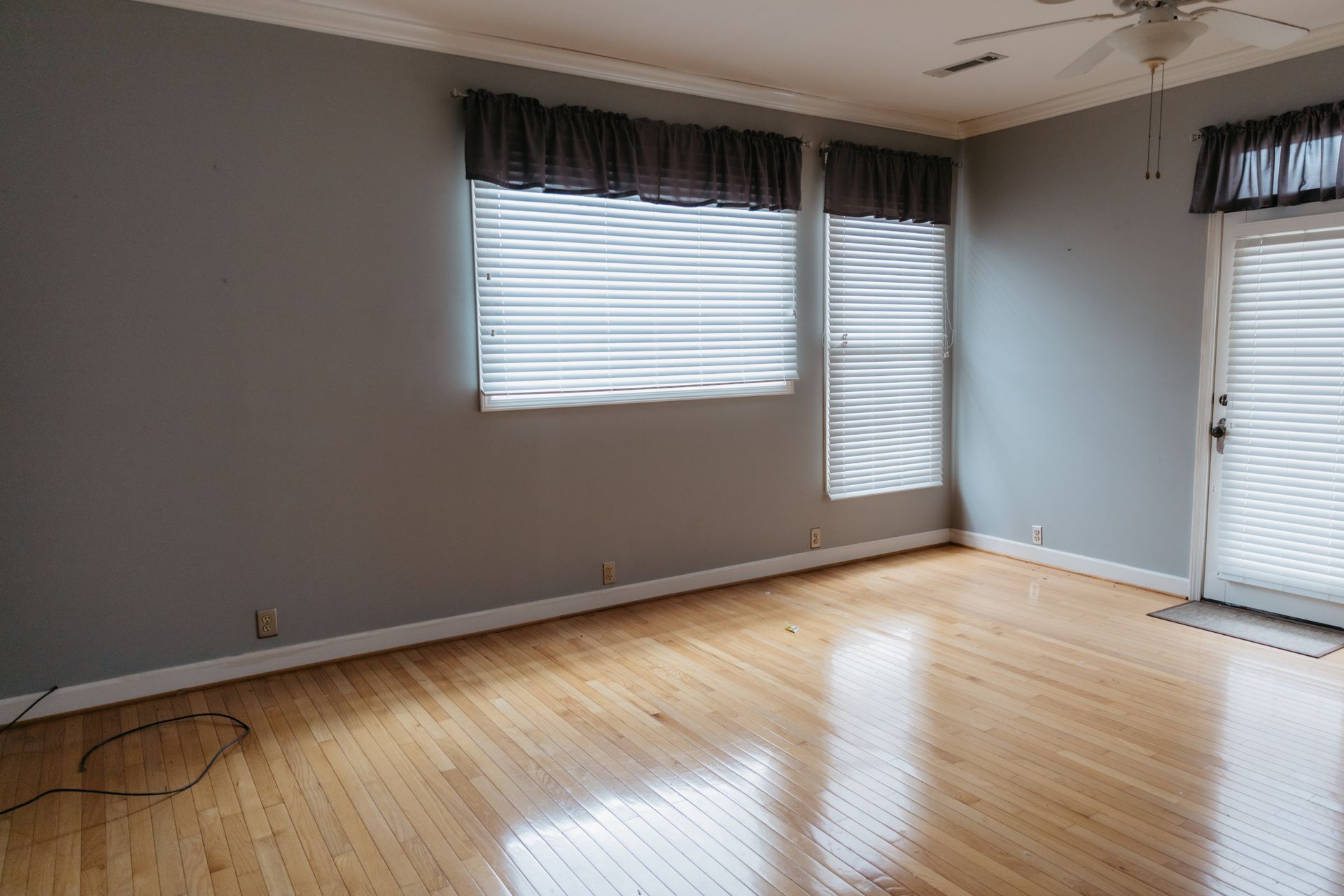 An empty living room with hardwood floors and a ceiling fan.