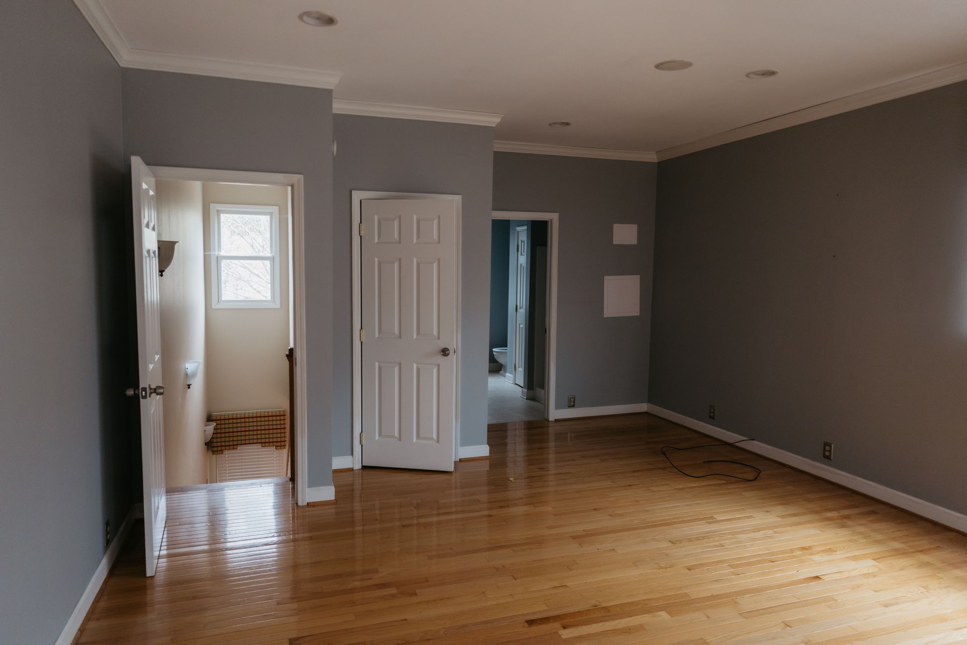 An empty room with hardwood floors and gray walls