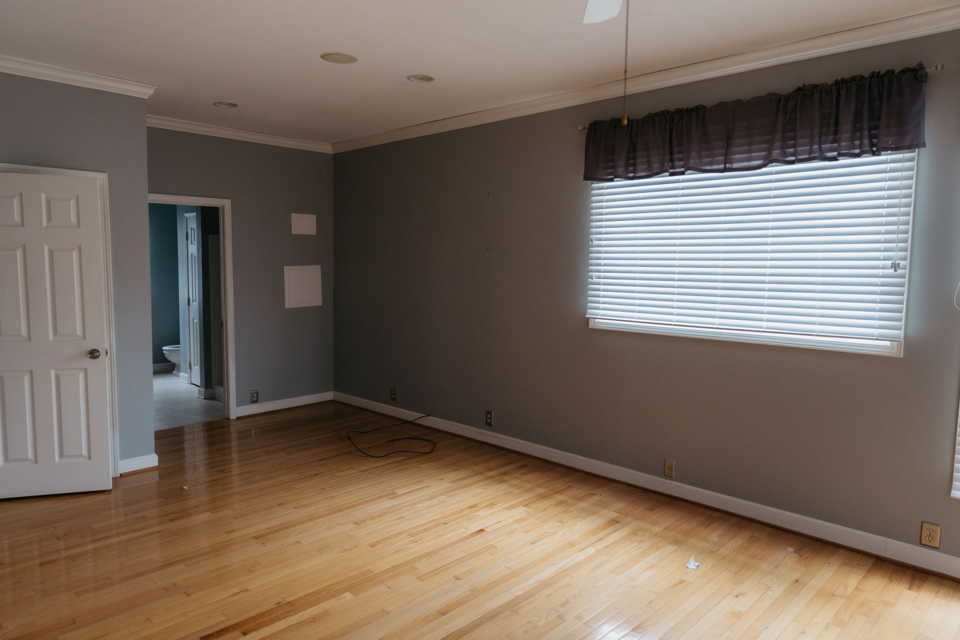A large empty room with hardwood floors and a window.