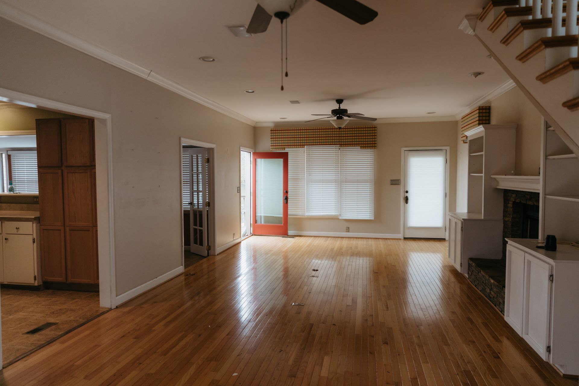 An empty living room with hardwood floors and a ceiling fan.