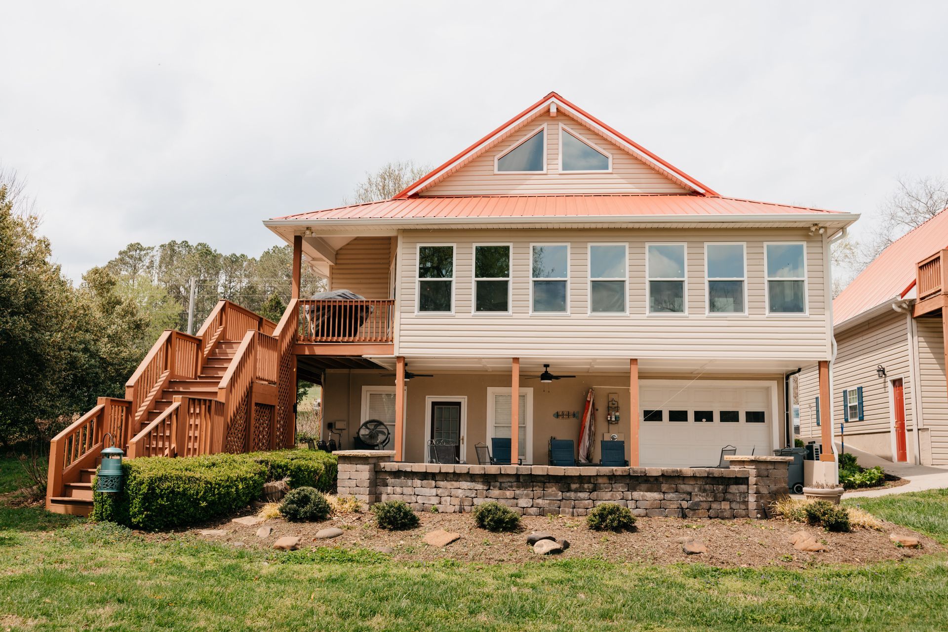 A large house with a red roof is sitting on top of a lush green field.