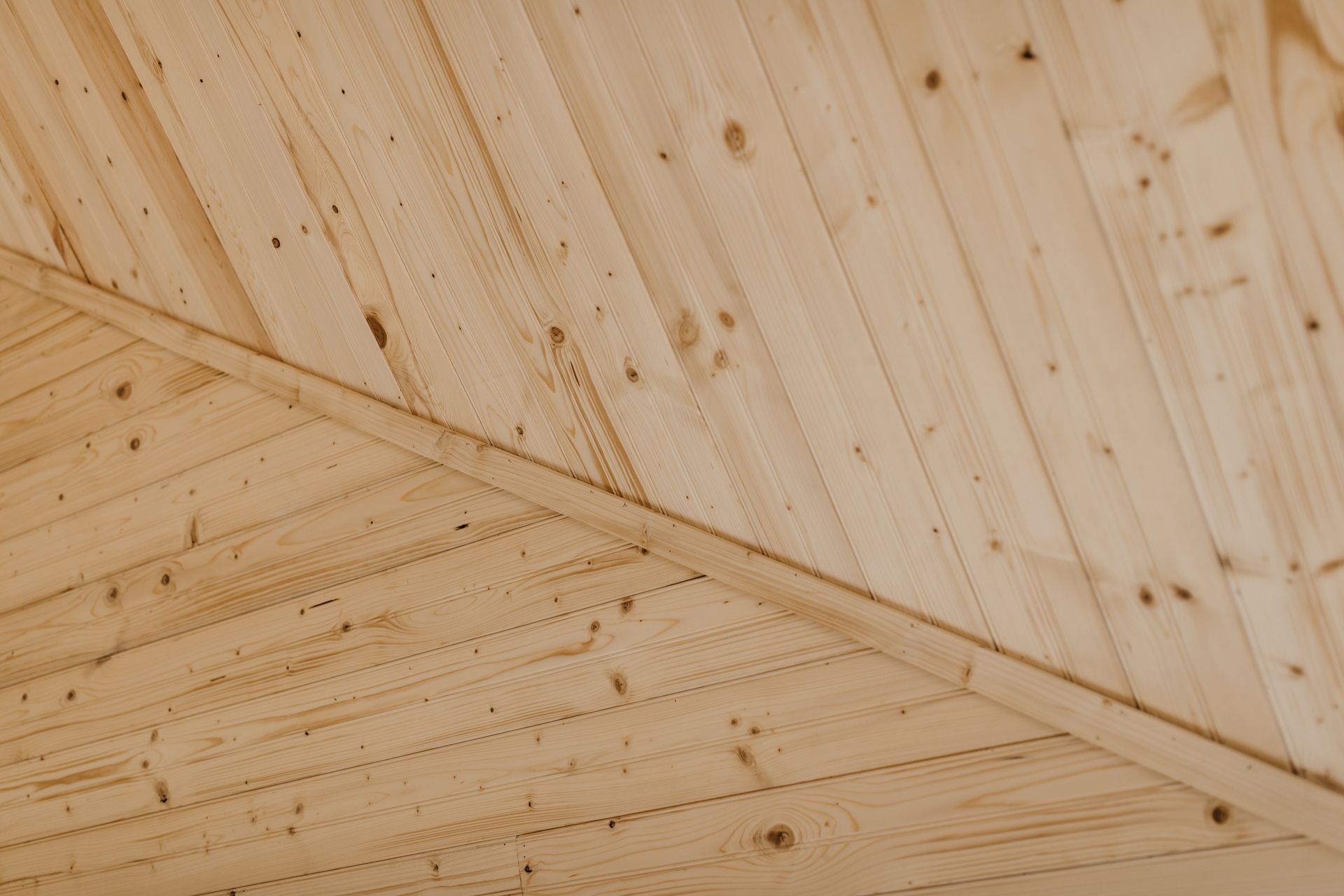 A close up of a wooden ceiling with a diagonal line.