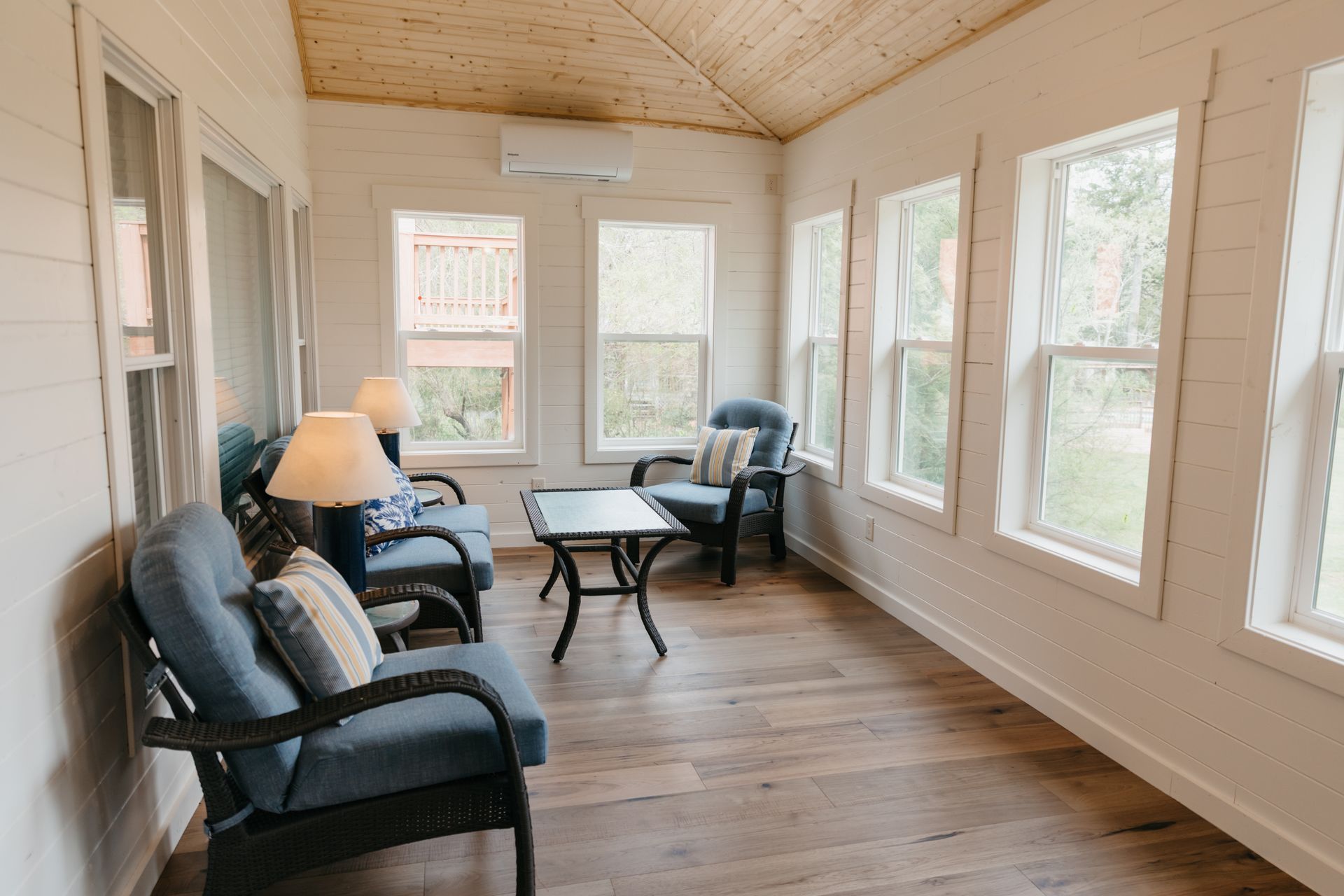 A living room with a lot of windows and chairs.