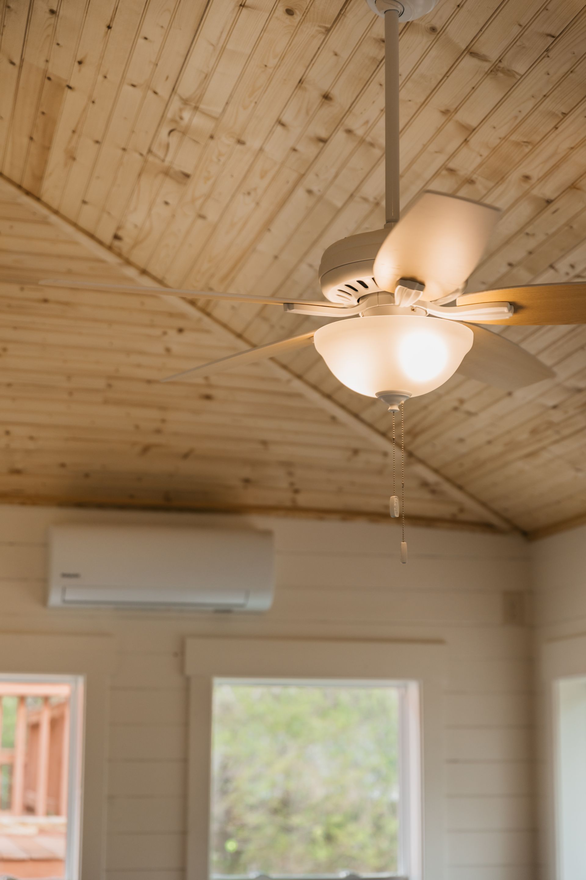 A ceiling fan is hanging from the ceiling of a room next to a window.