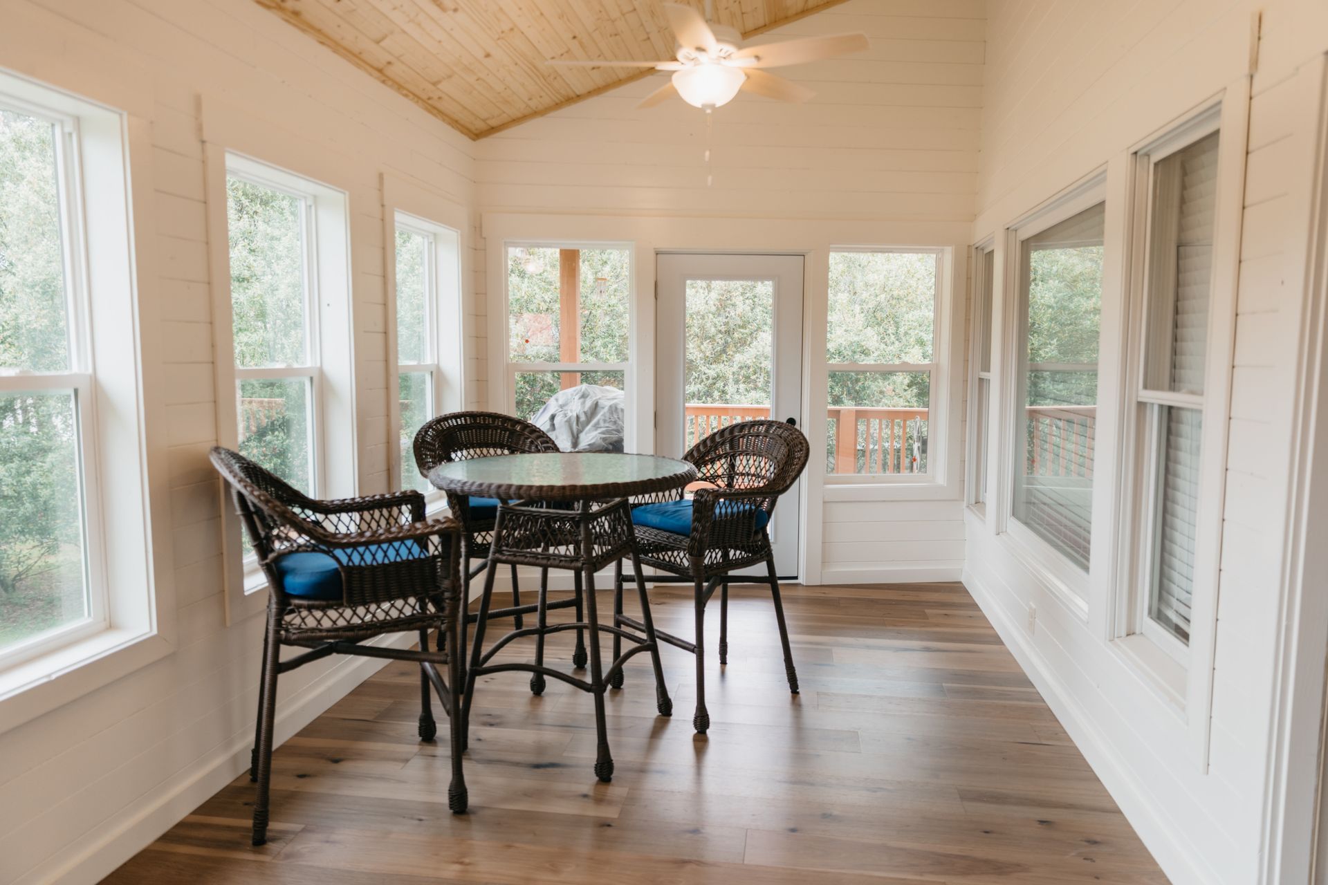 A sunroom with a table and chairs and a ceiling fan.