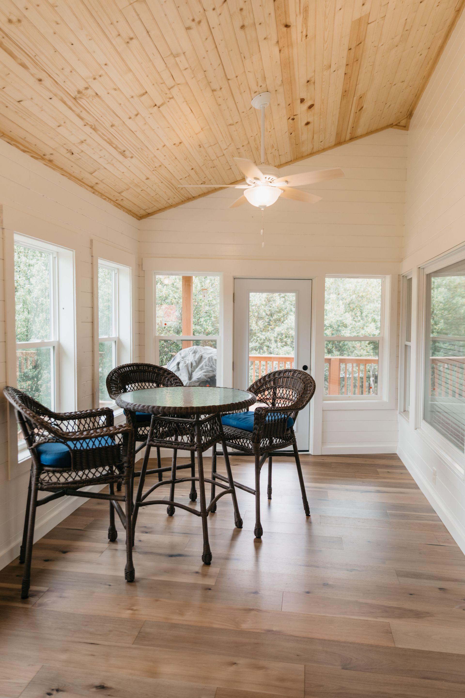There is a table and chairs in the room with a wooden ceiling.